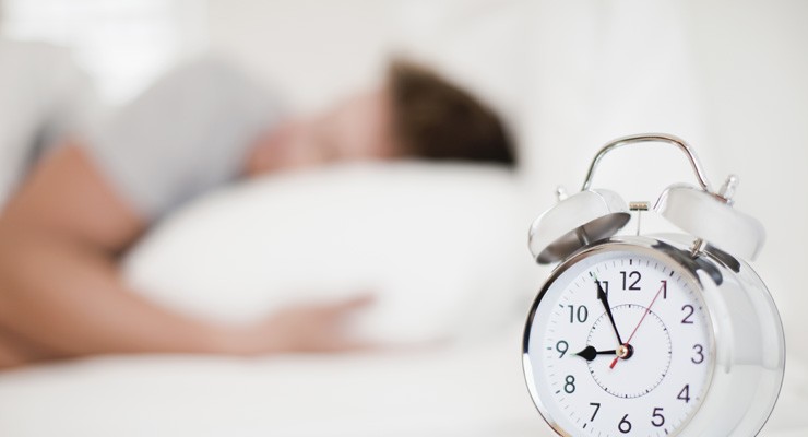0280_129944358 man sleeping with alarm clock in the foreground