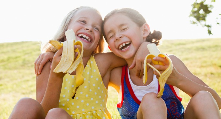 0086_155292082 two cute girls eating bananas